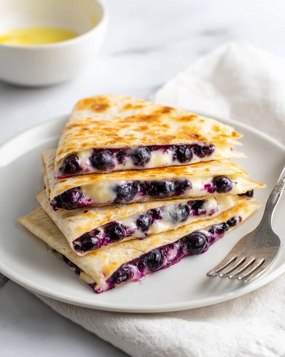 The image shows a white plate with four triangular pieces of quesadilla stacked on top of each other. Each quesadilla has a golden-brown crispy outer layer with a soft texture, filled with melted cream cheese and bursting, juicy, dark purple blueberries which slightly ooze out from the edges. The quesadilla layers are thin and show the contrast between the warm light golden tortilla and the dark, glossy blueberries inside. The plate sits on a white marbled surface with a soft white cloth napkin partly visible to the side, and a white bowl with a faint yellow residue in the blurry background, along with a silver fork placed on the plate beside the quesadilla pieces. photo taken with an iphone --ar 4:5 --v 7