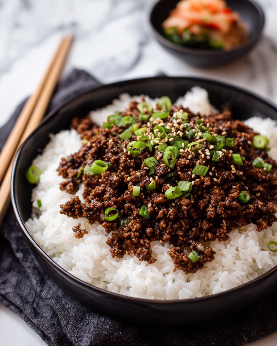 A black bowl sits on a white marbled surface, filled with three visible layers: the bottom layer is fluffy white rice with a soft texture, the middle layer is a generous amount of cooked minced meat in a rich brown sauce, and the top layer is sprinkled with bright green chopped scallions and light tan sesame seeds, adding freshness and crunch. In the background, there is another bowl that is out of focus and a pair of chopsticks resting on the surface. photo taken with an iphone --ar 4:5 --v 7
