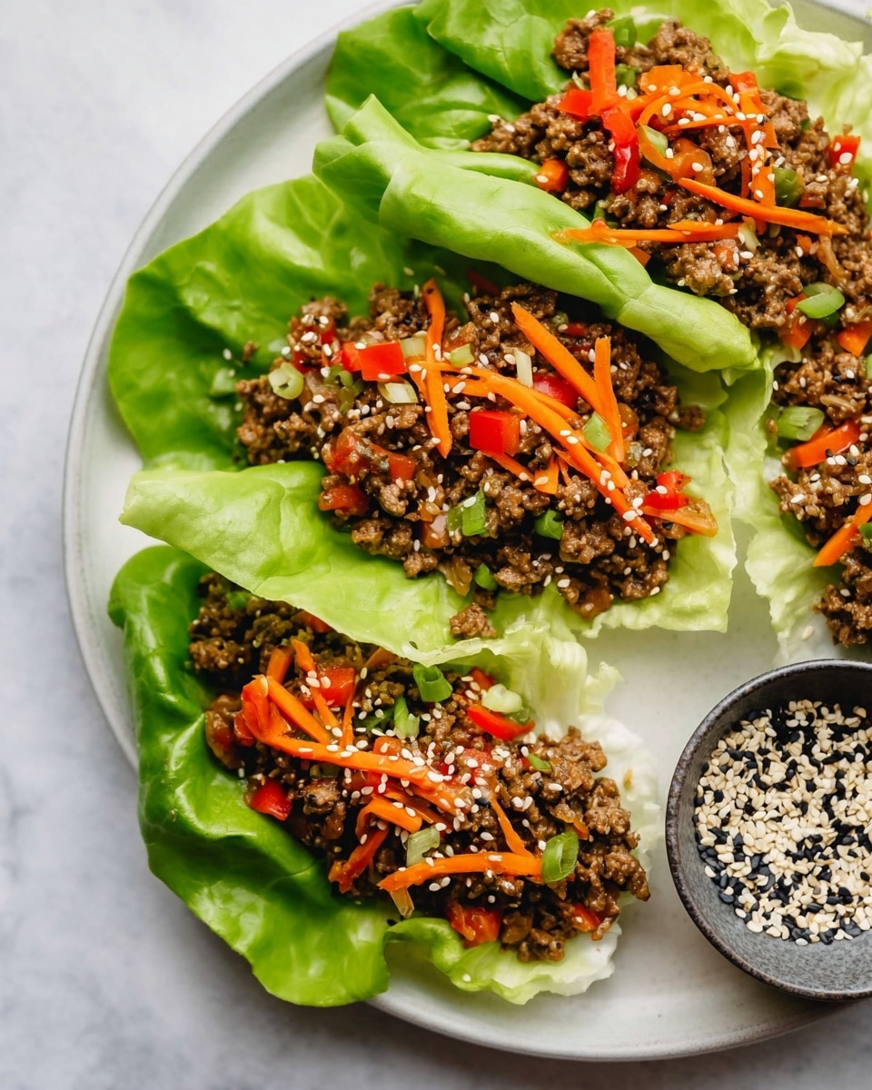 The image shows three lettuce wraps arranged closely on a white plate with a white marbled background. Each wrap consists of a large, fresh green lettuce leaf forming a cup at the base layer, filled with a mix of cooked ground meat and small diced orange and red bell peppers scattered throughout as the second layer. Thin strips of orange carrots add texture on top of the meat layer, while a sprinkling of black and white sesame seeds covers the whole filling, providing a contrasting speckled detail. On the right side of the plate, there is a small round bowl filled with a mixture of black and white sesame seeds. photo taken with an iphone --ar 4:5 --v 7