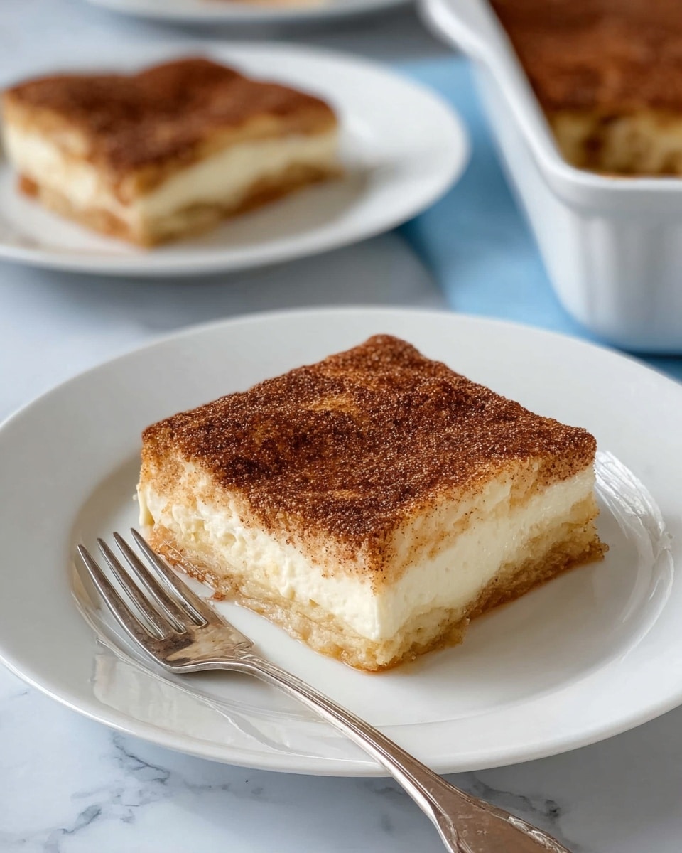 The image shows a square slice of a layered dessert on a white plate with a silver fork next to it. The dessert has three visible layers: a light golden-brown crust at the bottom, a thick creamy white middle layer, and a darker brown top layer sprinkled with a fine grainy texture, likely cinnamon sugar. In the background, there is another white plate with a similar dessert piece, and a white baking dish with the rest of the dessert inside. The setting is on a white marbled surface. Photo taken with an iphone --ar 4:5 --v 7