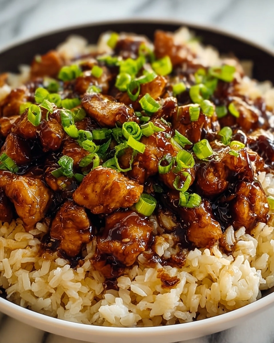 The dish shows two layers in a white bowl on a white marbled surface: the bottom layer is light brown cooked rice with visible grains, slightly shiny with oil, and the top layer is small, glossy dark brown pieces of chicken coated in a thick sauce, sprinkled with small bits of bright green chopped scallions on top. photo taken with an iphone --ar 4:5 --v 7