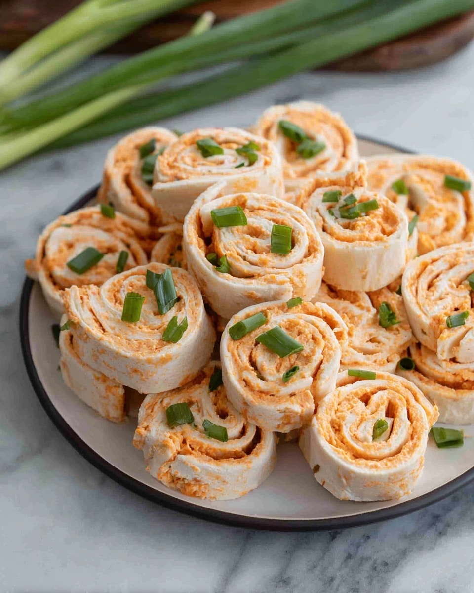 A round layer of white tortillas rolled with a creamy orange filling, cut into small spiral pinwheel shapes and stacked closely on a white plate. The orange filling layer is smooth with visible flecks of seasoning, spread evenly inside each tortilla. Small green pieces of chopped green onion are sprinkled over the rolls and some sit on top, adding a fresh contrast to the orange and white layers. The plate is placed on a white marbled surface, with whole green onions visible in the background. photo taken with an iphone --ar 4:5 --v 7