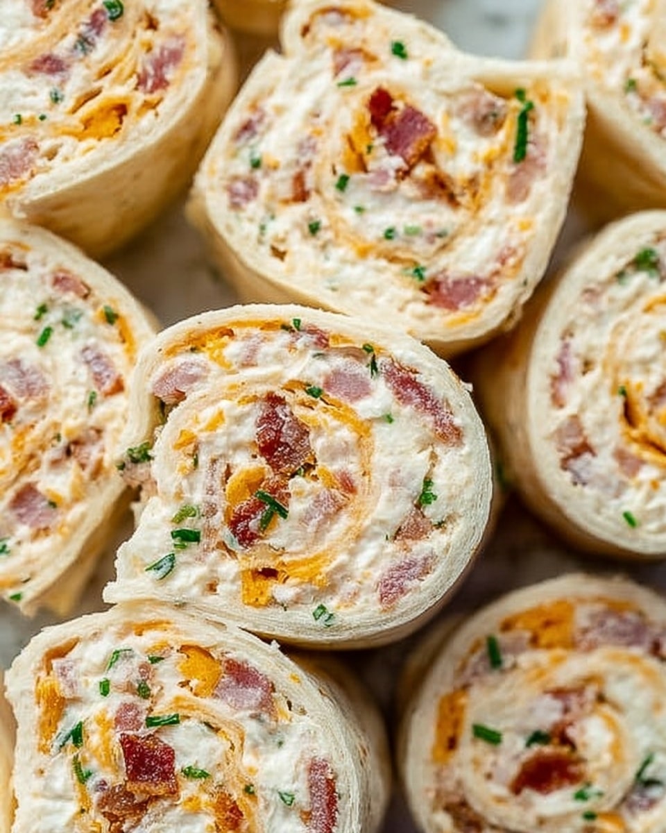 The image shows several small pinwheel sandwiches arranged close together on a white marbled surface. Each sandwich has three visible layers: the outer tortilla wrap is a soft, light beige color with a smooth texture; inside, there is a creamy white layer full of small orange cheese bits and small pink pieces, likely bacon; sprinkled throughout are tiny green herbs, adding a fresh pop of color. The pinwheels are sliced thick, showing a spiral pattern with a mix of colors and textures, all tightly rolled and evenly cut. The image captures a close-up view, focusing on the detail in each sandwich. Photo taken with an iphone --ar 4:5 --v 7